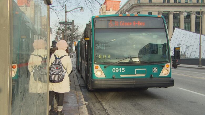 A bus pulls up to collect a passenger. 