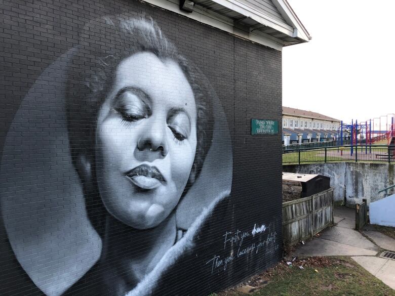 A mural of a woman's face on a wall outside.