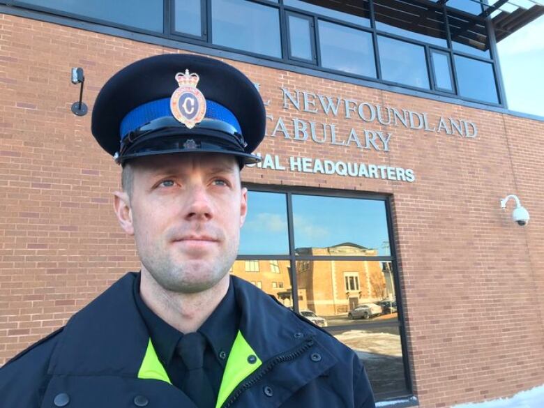 A police officer standing in front a brick police building.