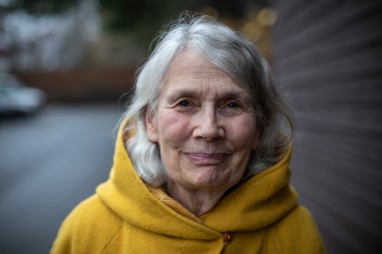 A white woman with white hair smiles in a close-up shot.