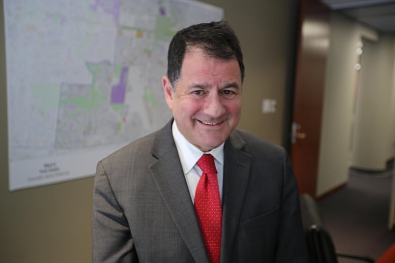 A man with a brown suit and brown hair smiling.