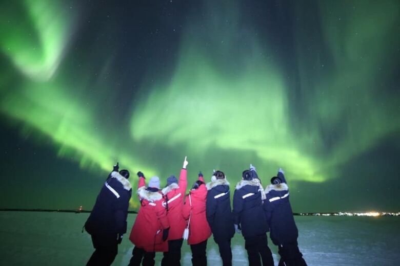 Tourists take a picture in under the northern lights in the winter