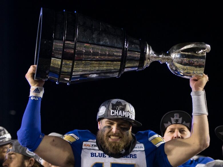 A man holds a large silver trophy over his head