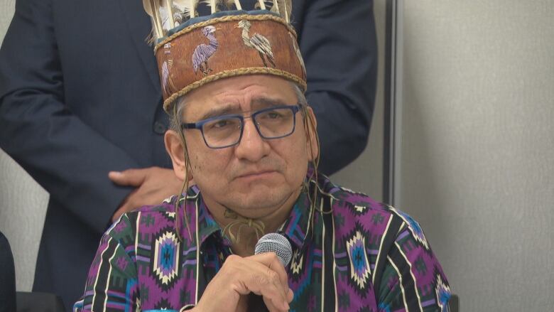 Man wearing a headress grips a microphone.