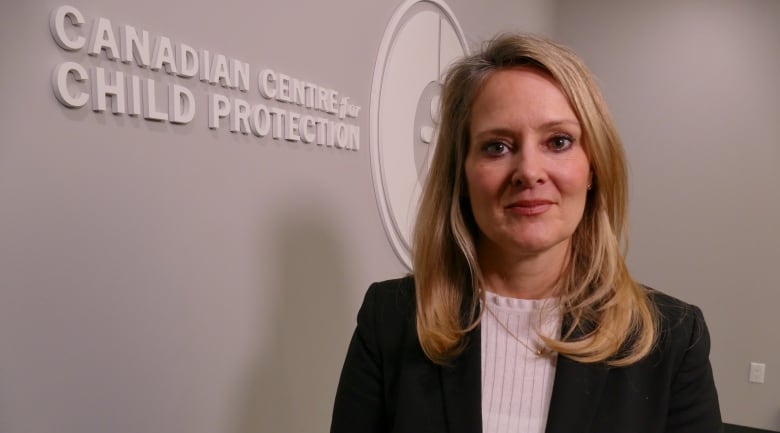 A woman in a black blazer poses for a photo, beside a logo for the Canadian Centre for Child Protection.