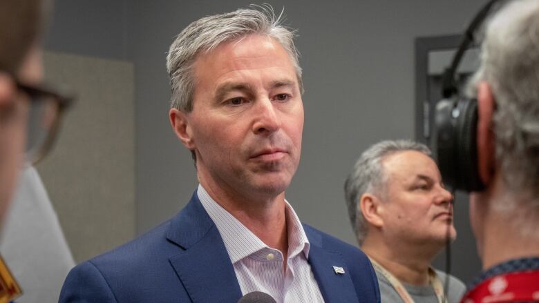 A white man with grey hair wearing a navy suit