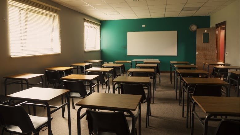 Desks are pictured in an empty classroom.