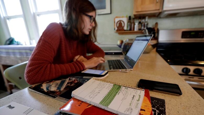 A student works on a laptop at a kitchen counter.