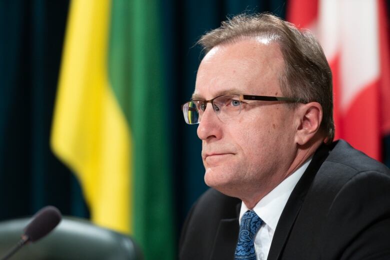 Man Speaking at a press conference with the Canada and Saskatchewan Flag behind him