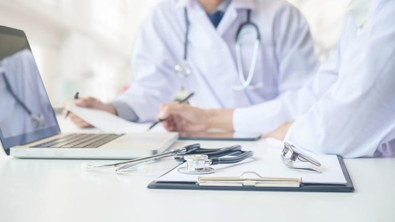 A stock image of doctors in lab coats working at a desk, with stethoscopes visible.