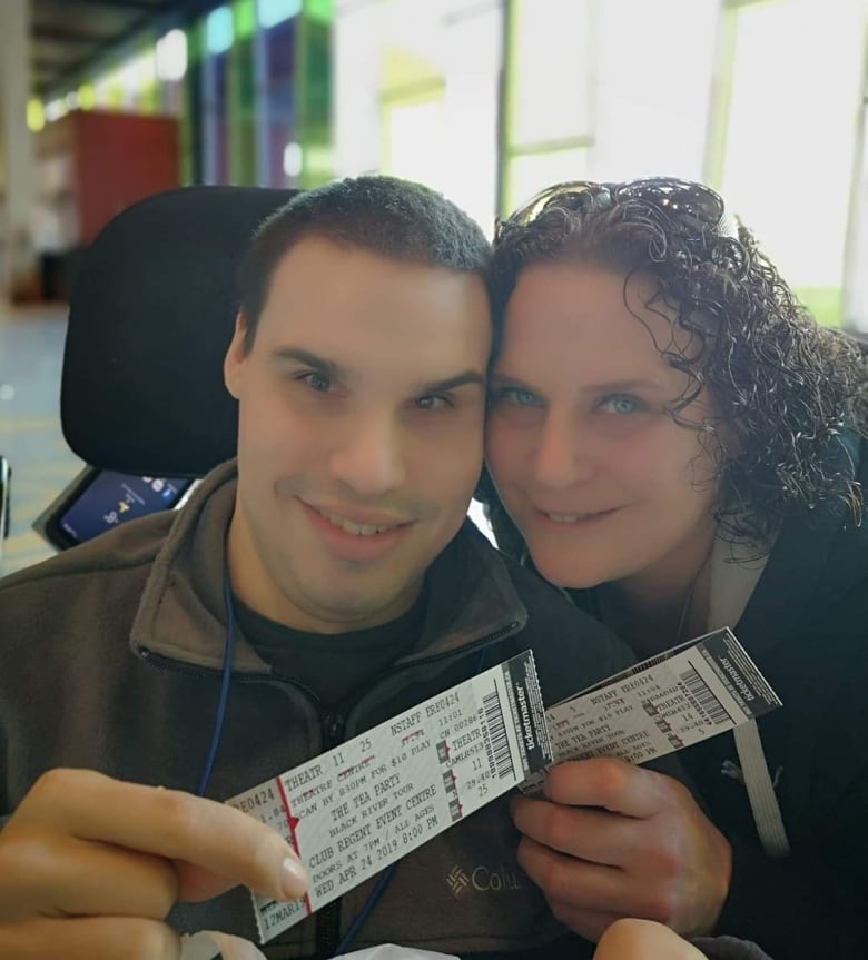 Close photo of a young man at left and an older woman, the man's mother, on the right. They are holding ticket stubs.