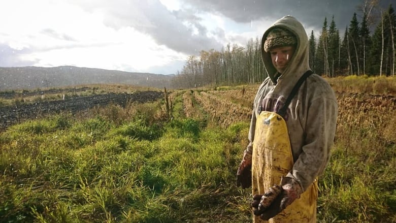 A man in coveralls on in a muddy field.