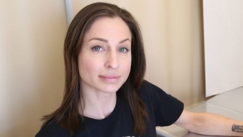 A woman with brown hair wear a black t-shirt that says Naloxone saves lives