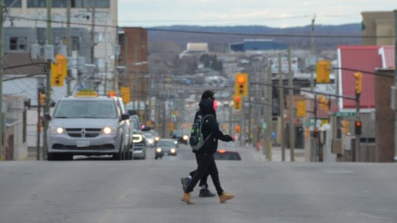 Two people walk across Algonquin road in Timmins