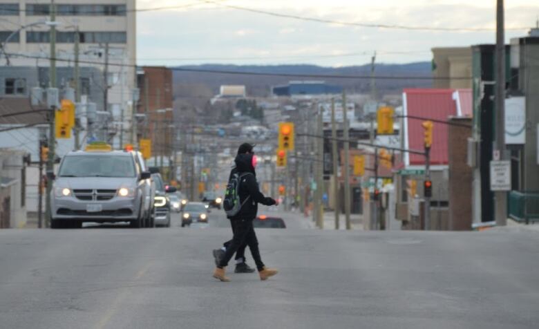 Two people walk across Algonquin road in Timmins