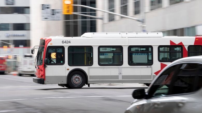 A bus drives down a busy road, with the background blurred.