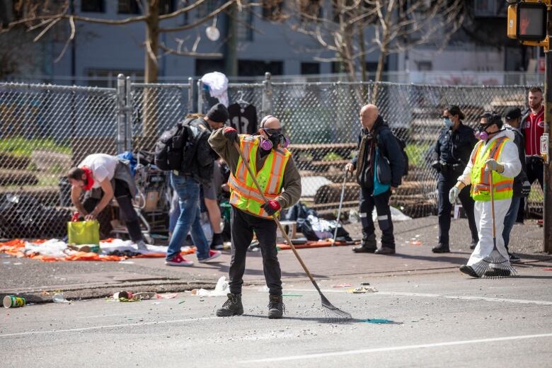 A group of city workers in high-vis jackets clean a street.