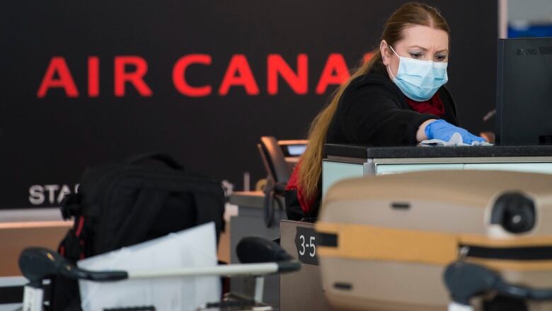 An Air Canada worker cleans her ticketing station at Pearson International Airport in Toronto on Wednesday, April 8, 2020.