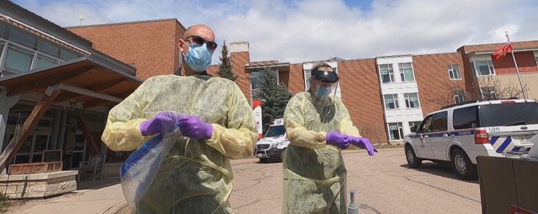 paramedics wear protective gear outside a building