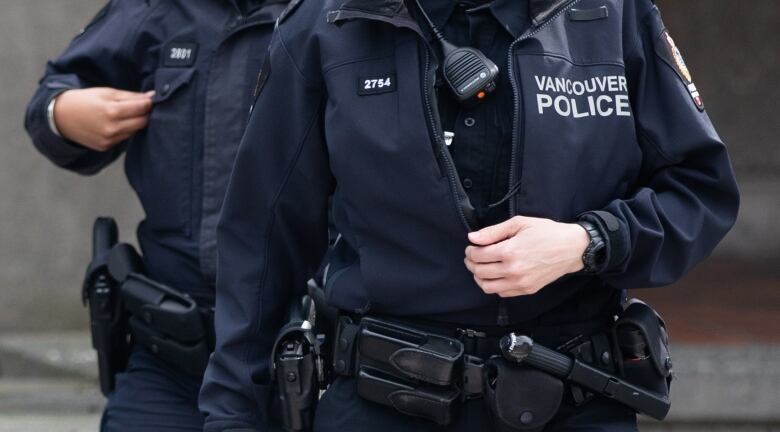 A close up picture of two Vancouver Police officers with jackets and walkie-talkies on their chests.