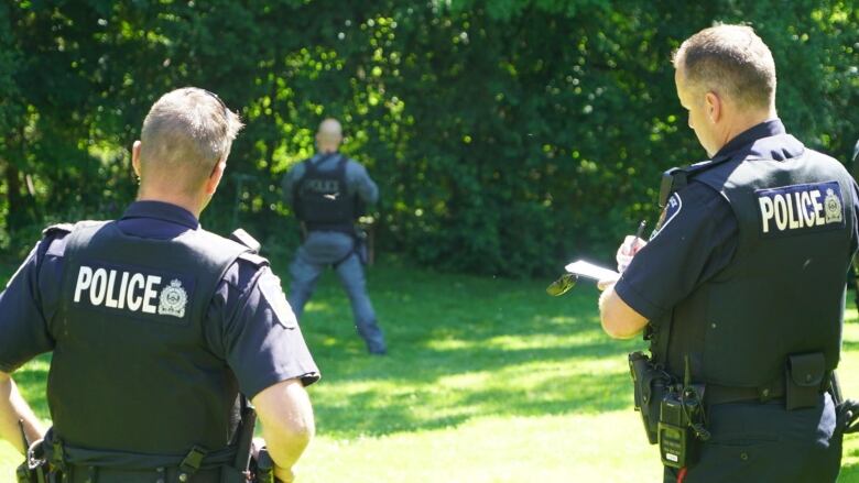 London police officers stand in a field. 