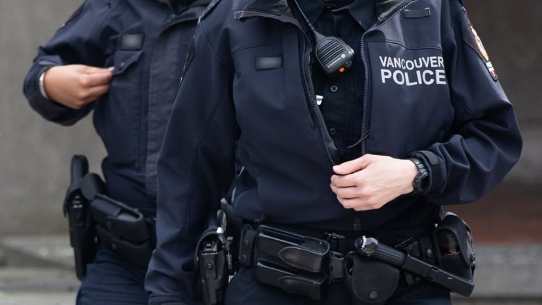 A close up picture of two Vancouver Police officers with jackets and walkie-talkies on their chests.