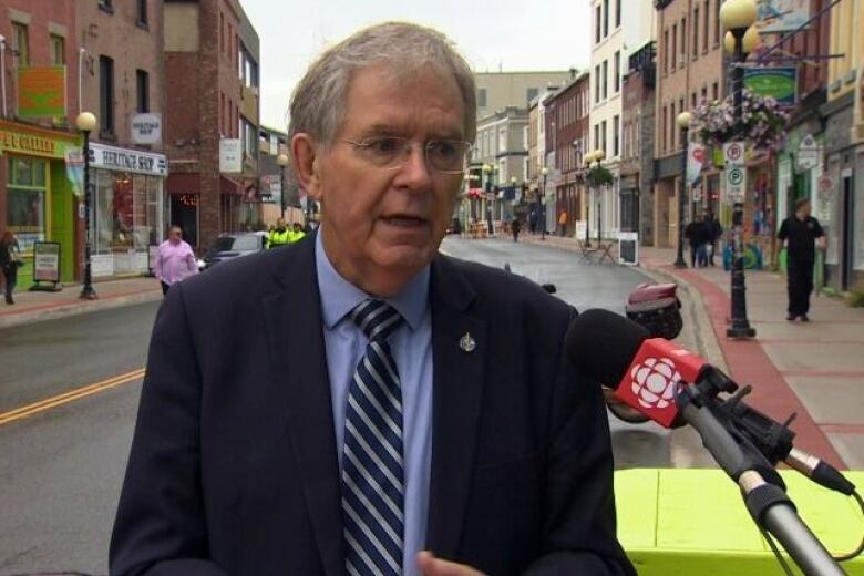 A man in a suit stands on a downtown city street.