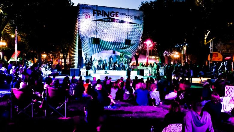 A crowd is pictured watching musical acts perform on stage at night.