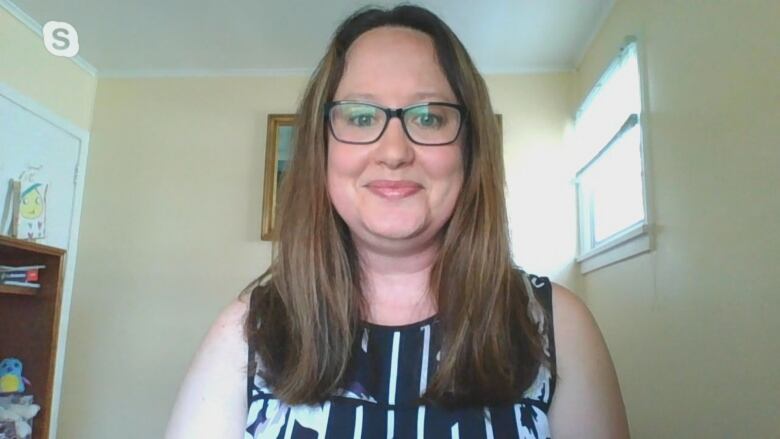 Woman with glasses with window in background.