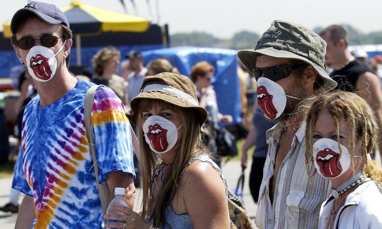 Four concert-goers wearing masks with cartoon mouth logo over their mouths