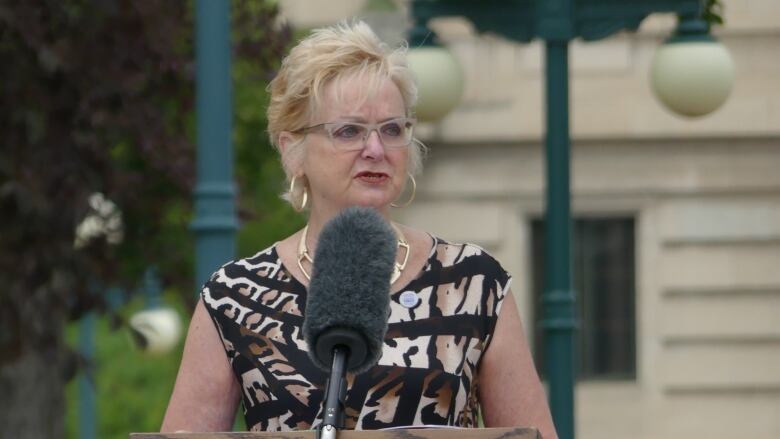 A woman stands behind a microphone.