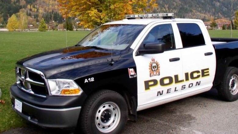 A black-and-white short pickup truck. It has a police badge and text that reads 'POLICE Nelson' on the side.