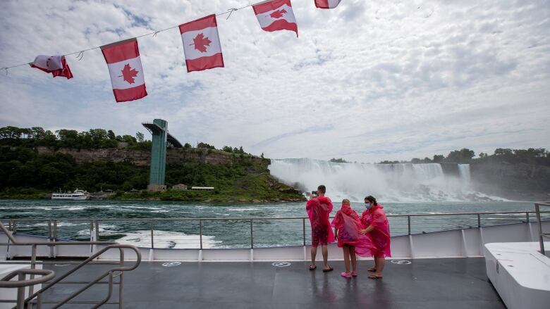 people in ponchos stand on boat deck