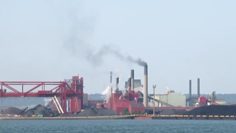 Piles of coal and smokestacks with black smoke coming out are seen in a photo of Dofasco taken from the water.