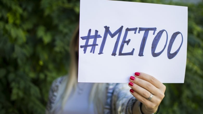 A woman's hand holds a #MeToo sign.