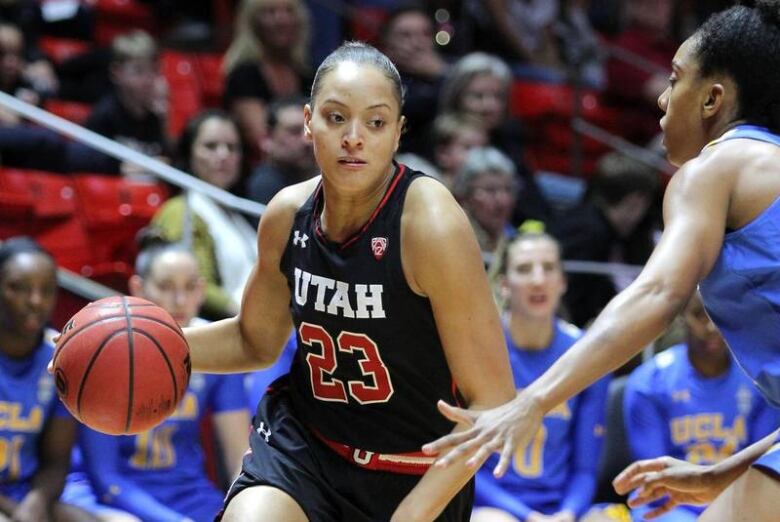 A Black woman in a basketball court dribbling a ball