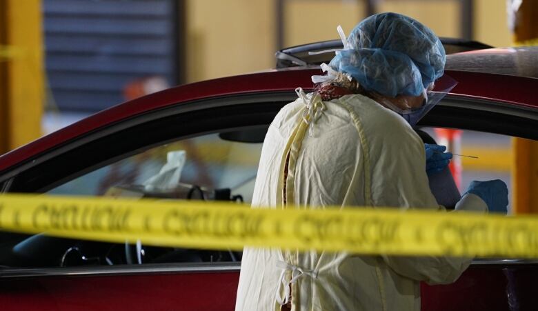 A person being tested for COVID in their car is shown.