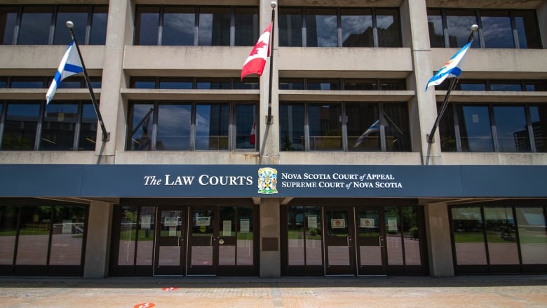 A concrete and glass building with the flags of Nova Scotia and Canada.