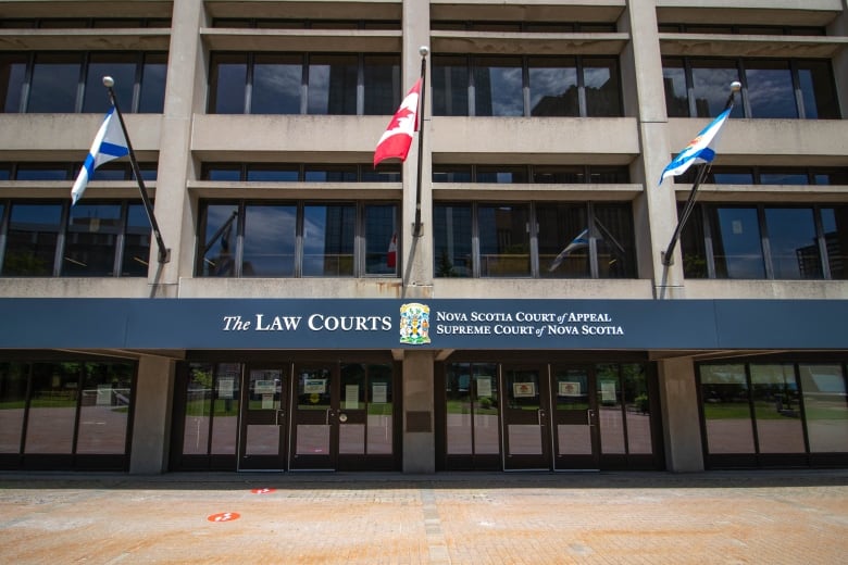 A concrete and glass building with the flags of Nova Scotia and Canada.