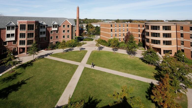 A large green space is surrounded by red brick buildings.