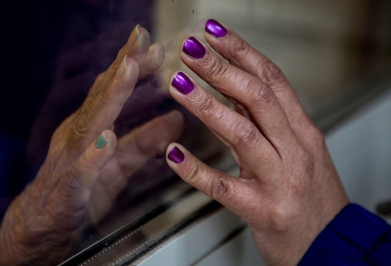 Two hand both touching against a piece of glass between them