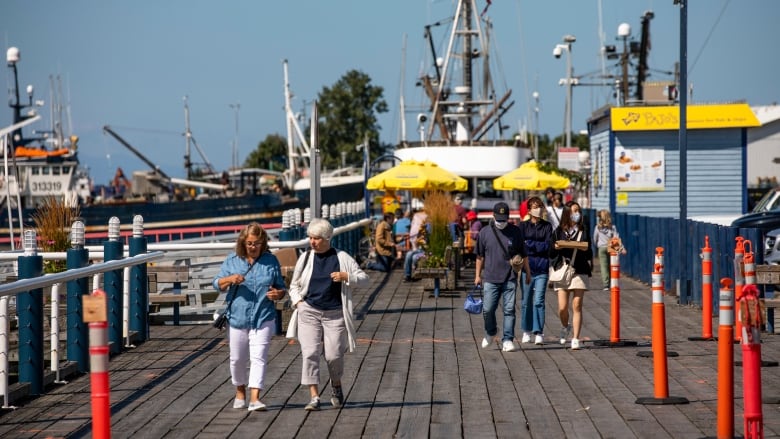 People walk along a boardwalk on a sunny day.