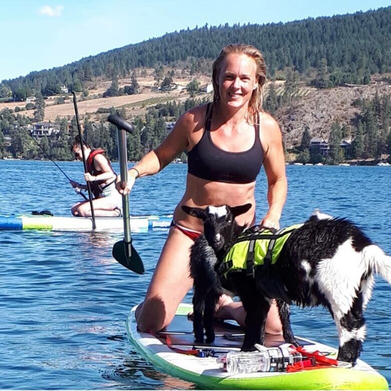 Woman paddling in a boat with a goat.