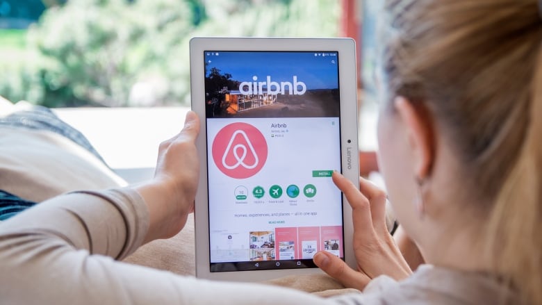 Generic photo of woman looking at tablet with Airbnb site open.