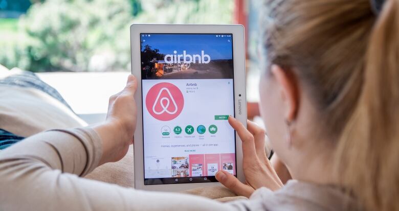 Generic photo of woman looking at tablet with Airbnb site open.