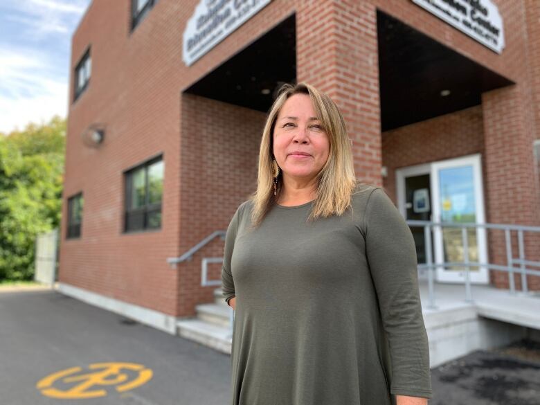 A woman stands in front of a brick building.