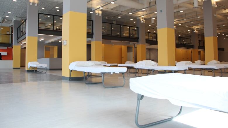 This photo shows a large room with cots lined up in rows. 