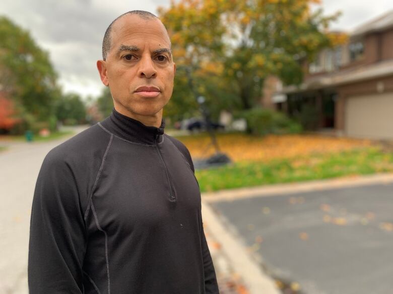 A man stands on a residential street.