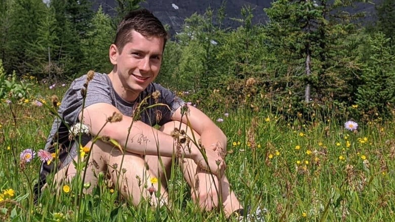 Young man sitting in a field.