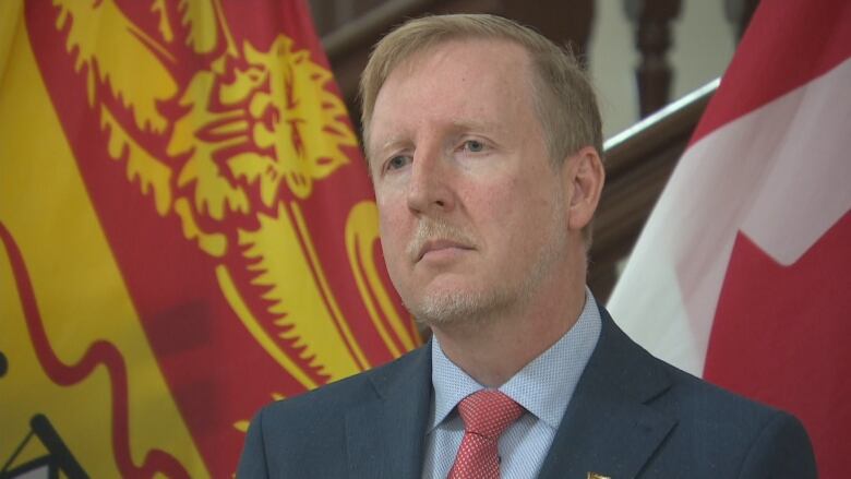 Dominic Cardy is photographed in front of Canadian and New Brunswick flags.